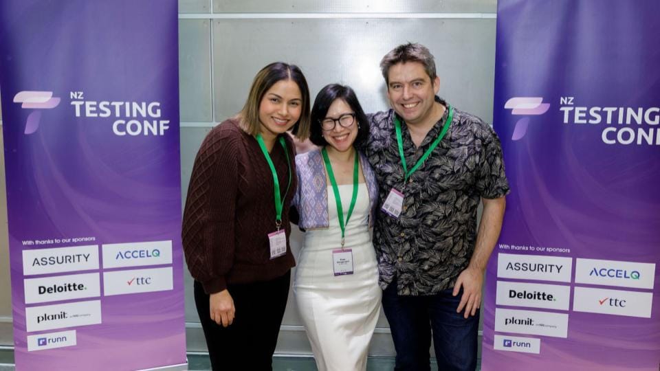 Co-founders of NZ Tech Rally co-founders: Camy, me, and Aaron, standing together in front of NZTestingConf 2024 banners